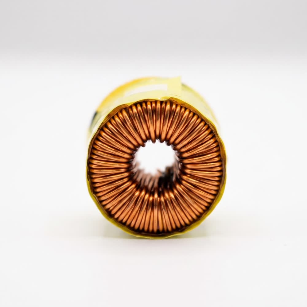 A copper wound toroid taped in yellow, seen down its axis
